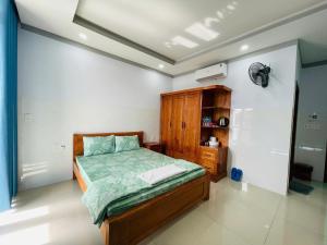 a bedroom with a bed and a wooden cabinet at Hotel Trâm Anh 1 in Nhơn Trạch