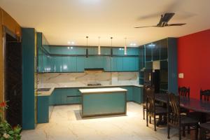 a kitchen with blue cabinets and a table with chairs at Hotel Konaaz Inn in Alīgarh