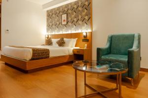 a bedroom with a bed and a chair and a table at Hotel Sky International in Kizhake Chālakudi +52 photos