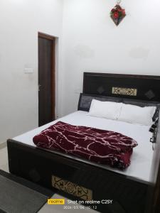 a bedroom with a bed with a burgundy blanket on it at Radha Rani homestay in Vrindāvan