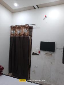 a room with a curtain and a tv on a wall at Radha Rani homestay in Vrindāvan