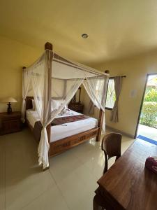 a bedroom with a canopy bed and a table at Ariartha homestay in Ubud