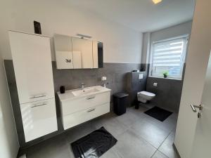 a bathroom with a white sink and a toilet at Sauerland Wellness Apartment mit Sauna und Jacuzzi in Olpe +14 photos