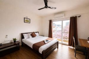 a bedroom with a bed and a window and a desk at Coffee Bean Inn in Bangalore