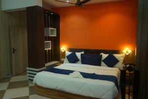 a bedroom with a large bed with an orange wall at Hotel Konaaz Inn in Alīgarh