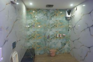 a bathroom with a shower with a marble wall at Hotel Konaaz Inn in Alīgarh +76 photos