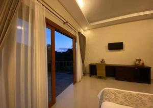 a bedroom with a bed and a sliding glass door at Nadira BnB in Munduk