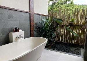 a white bath tub in a bathroom with a fence at Nadira BnB in Munduk