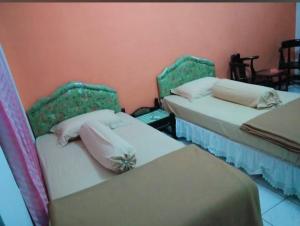 a room with two beds with pillows on them at Hotel Permata Inn Ball Room Seroja in Kualakapuas +5 photos
