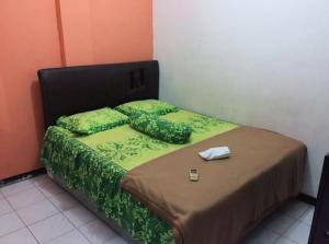 a bedroom with a bed with green sheets and pillows at Hotel Permata Inn Ball Room Seroja in Kualakapuas