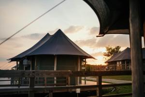 a building with a pitched roof with the sunset in the background at Greenfields Glamping Durbuy in Durbuy