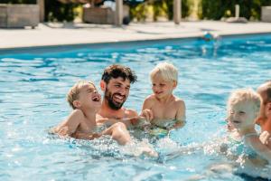a man and children in a swimming pool at Greenfields Glamping Durbuy in Durbuy