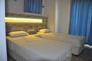 two beds in a hotel room with blue curtains at Nur Hotel in Kaş
