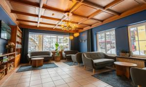 a waiting room with chairs and tables and windows at Hotel Pinzgauerhof by Alpeffect Hotels in Zell am See