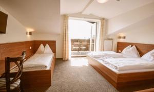 a bedroom with two beds and a large window at Hotel Pinzgauerhof by Alpeffect Hotels in Zell am See