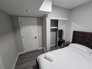 a bedroom with a white bed and a white door at Cozy 2 Bedroom basement Suite in Calgary