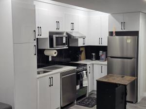 a kitchen with white cabinets and stainless steel appliances at Cozy 2 Bedroom basement Suite in Calgary
