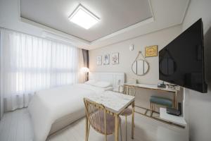 a hotel room with a bed and a table and a television at Daegu lily Residence Hotel in Daegu
