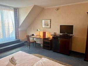 a hotel room with a desk and a television at Akzent Hotel Höltje in Verden