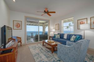 a living room with a blue couch and a tv at Oceanfront Condo Halii Kai 14D in Waikoloa