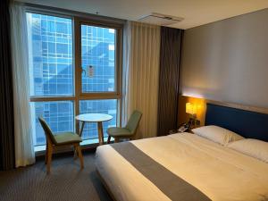 a hotel room with a bed and a table and a window at 센텀스위트호텔 in Busan
