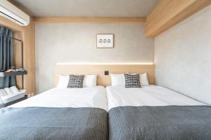two beds sitting next to each other in a bedroom at b&新大阪店 in Osaka