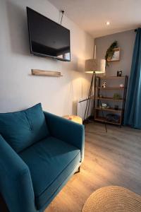 a living room with a blue couch and a flat screen tv at Le petit nid de St-Germain in Saint-Germain