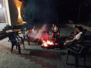 a group of people sitting around a fire at HALASE HOMESTAY mudigere in Mudigere