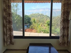 a room with a window with a view of the mountains at Arav Resort in Katrab