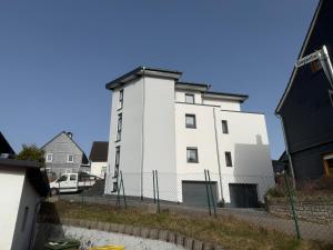 a white building with a fence in front of it at Sauerland Wellness Apartment mit Sauna und Jacuzzi in Olpe