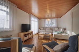 a living room with a couch and a tv at Cozy traditional Chalet, Stunning Mountain Views in Grindelwald