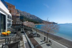 a balcony with tables and chairs and a view of the water at Wind Rose Maestral-beachfront in Igrane