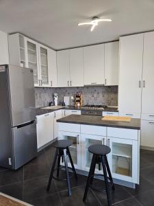 a kitchen with white cabinets and two bar stools at Apartment Rita in Mokošica +21 photos