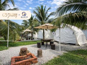 a tent with a table and a bench and an umbrella at The Coco Journey - Eco Tent in Kelebang Besar
