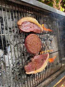 three pieces of meat cooking on a grill at B&B Casa Lupi in Ronchi