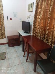 a room with a desk and a television and a table at Buena Lynnes Annex Lodge in Puerto Galera