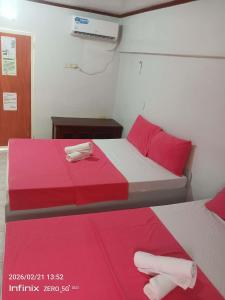 a bedroom with two beds with red and white sheets at Buena Lynnes Annex Lodge in Puerto Galera