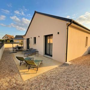 a building with chairs and tables on a patio at Villa Saint Mart-Tout Inclus-Plage à 7 min à pied in Saint Martin de Brehal