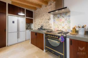 a kitchen with a stove and a refrigerator at Casa Abeurador, con mucho encanto en el centro de Artà in Artá
