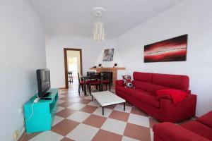 a living room with a red couch and a tv at Chalet Amanecer Chiclana in Novo Sancti Petri