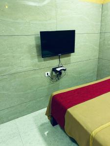 a room with a tv on a wall with a bed at GSR RESIDENCy in Kanchipuram +6 photos