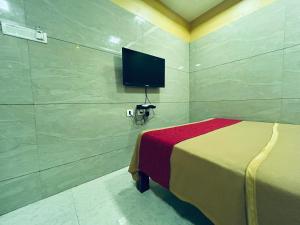 a bedroom with a bed and a tv on the wall at GSR RESIDENCy in Kanchipuram