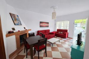 a living room with a red couch and a table at Chalet Amanecer Chiclana in Novo Sancti Petri +9 photos