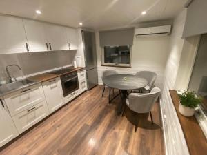 a kitchen with white cabinets and a table and chairs at Port Hotel Ocean Villa in Karlshamn