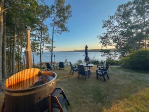 a backyard with a hot tub and tables and chairs at Lucky Stone Retreat - private beach & Acadia view in Sullivan