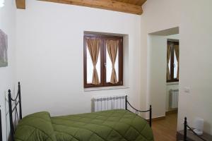 a bedroom with a green bed and two windows at Affittacamera La Dormiente in Torrecuso