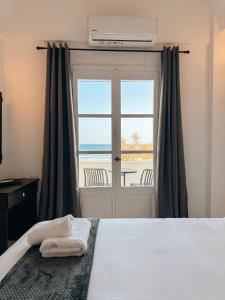 a bedroom with a bed and a window with a view of the ocean at Aegean Nest Beach Studios - Adults only in Monolithos