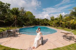 a bride standing in front of a swimming pool at Sim Forest Resort in Phú Quốc