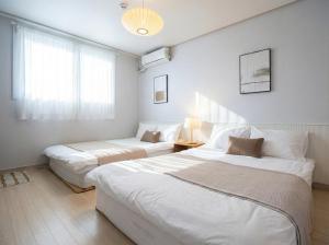 two beds in a room with white walls at Seoul 3R,4B,2BA,All rooms AC, 지하철도보5분, 동대문15분, 명동25분, 이태원,성수,서울역 30분 in Seoul