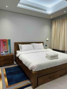 a bedroom with a large bed with white sheets at Eid Holiday in Muscat